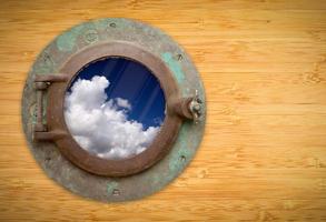 antiek patrijspoort Aan bamboe muur met visie van blauw lucht en wolken foto