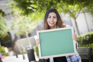 opgewonden gemengd ras vrouw leerling Holding blanco schoolbord foto