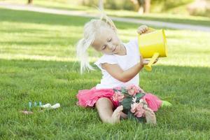schattig weinig meisje spelen tuinman met haar gereedschap en bloem pot. foto