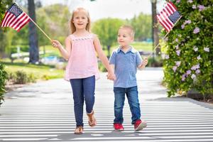 jong zus en broer golvend Amerikaans vlaggen Bij de park foto