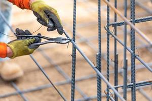 arbeider beveiligen staal wapening framing met draad tang snijder gereedschap Bij bouw plaats foto