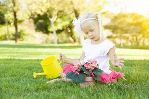 schattig weinig meisje spelen tuinman met haar gereedschap en bloem pot. foto