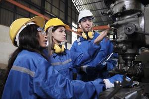 een industrieel arbeiders team in beschermend en veiligheid uniformen en harde hoeden, mannetje manager, en vrouw collega's werk met metaalwerk machines in fabricage fabriek. professioneel productie ingenieur. foto