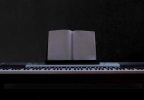 elektrisch piano met leeg vel muziek- Aan zwart achtergrond, piano toetsenbord Aan donker achtergrond concept kunst, voorkant visie foto
