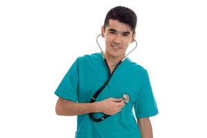 portret van jong mooi brunette Mens dokter in blauw uniform met stethoscoop op zoek en glimlachen Aan camera geïsoleerd Aan wit achtergrond foto