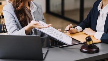 mannelijke advocaat die met contractdocumenten en houten hamer op tafel in rechtszaal werkt. justitie en recht, advocaat, rechter, concept. foto