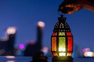 lantaarn en klein bord van datums fruit met stad achtergrond voor de moslim feest van de heilig maand van Ramadan kareem. foto