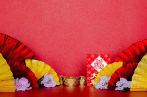 rood envelop pakketten of ang bao woord gemeen rijkdom, Lucky en blokken met gouden en rood oosters fans met perzik bloesem Aan rood achtergrond voor Chinese nieuw jaar concept. foto
