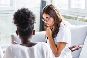 dokter werken in de kantoor en luisteren naar de geduldig, ze is uitleggen haar symptomen, gezondheidszorg en bijstand concept echt dokter met klembord en geduldig in ziekenhuis. foto