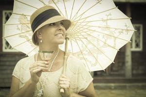 Jaren 1920 gekleed meisje met parasol en glas van wijn portret foto