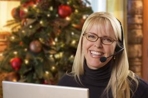 vrouw met telefoon koptelefoon in voorkant van Kerstmis boom, computer foto