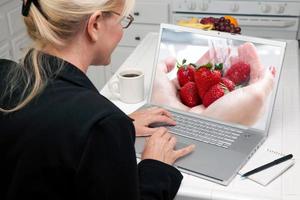 vrouw in keuken gebruik makend van laptop - voedsel en recepten foto