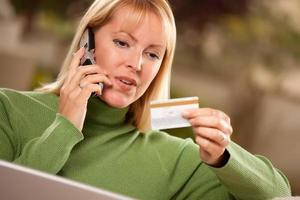 vrolijk vrouw Aan telefoon en laptop met credit kaart foto