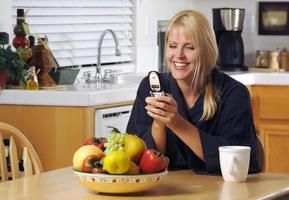 vrouw in keuken gebruik makend van cel telefoon foto