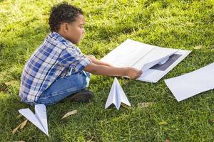 gemengd ras jongen aan het leren hoe naar vouwen papier vliegtuigen foto