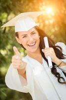 afstuderen gemengd ras meisje in pet en japon met diploma foto