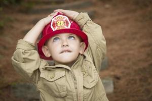 aanbiddelijk kind jongen met brandweerman hoed spelen buiten foto