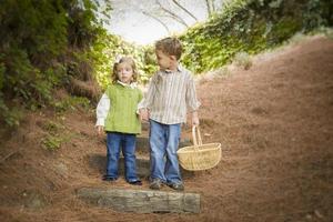 twee kinderen wandelen naar beneden hout stappen met mand buiten. foto