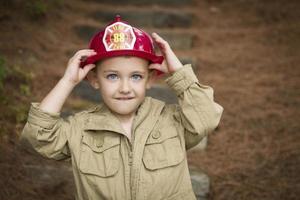 aanbiddelijk kind jongen met brandweerman hoed spelen buiten foto