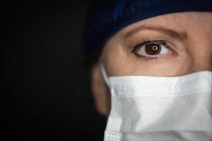 vrouw dokter of verpleegster vervelend medisch gezicht masker Aan donker achtergrond foto