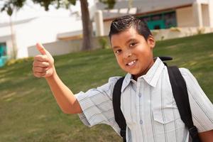 gelukkig jong spaans school- jongen met duimen omhoog foto