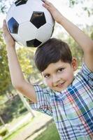 schattige jonge jongen spelen met voetbal in park foto