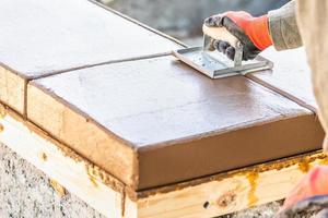 bouw arbeider gebruik makend van hand- groover Aan nat cement vormen omgaan in de omgeving van nieuw zwembad foto