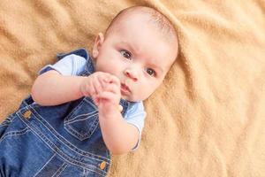 gelukkig gemengd ras baby jongen houdende Aan deken foto