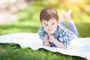gemengd ras Chinese en Kaukasisch jong jongen ontspannende buiten Aan de gras foto