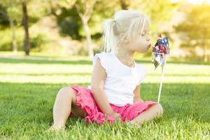 weinig meisje in gras blazen Aan pinwheel foto