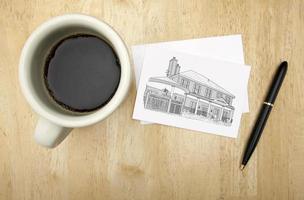 Notitie kaart met huis tekening, pen en koffie foto
