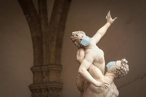 de ontvoering van de sabine Dames standbeeld door giambologna, in de loggia dei lanzi in Florence Italië met gezicht maskers - coronavirus laten schrikken foto