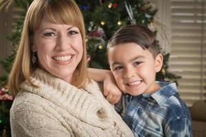 moeder en gemengd ras zoon knuffel in de buurt Kerstmis boom foto