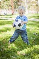 jong schattig jongen spelen met voetbal bal in park foto