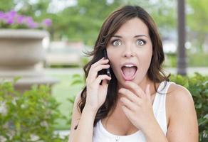 geschokt jong volwassen vrouw pratend Aan cel telefoon buitenshuis foto