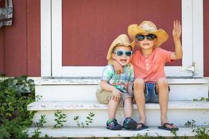 gemengd ras Chinese en Kaukasisch jong broers hebben pret vervelend zonnebril en cowboy hoeden foto
