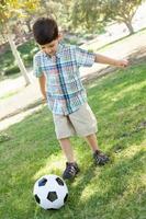 schattige jonge jongen speelt met voetbal buiten in het park. foto