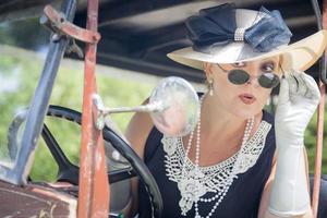 aantrekkelijk vrouw in jaren twintig kleding controle bedenken in antiek auto- foto