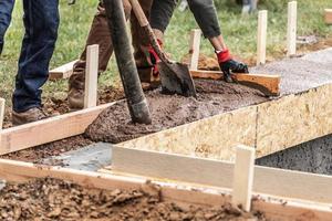 bouw arbeiders gieten en nivelleren nat cement in hout framing foto