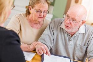 senior volwassen paar gaan over- documenten in hun huis met middel Bij ondertekening foto