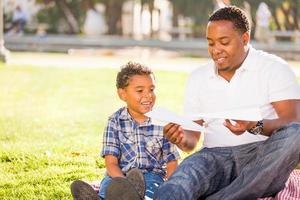 gelukkig Afrikaanse Amerikaans vader en gemengd ras zoon spelen met papier vliegtuigen in de park