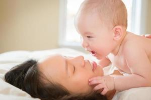 gemengd ras Chinese en Kaukasisch baby jongen houdende in bed met zijn moeder foto