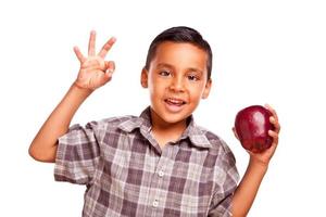 aanbiddelijk spaans jongen met appel en Oke hand- teken foto
