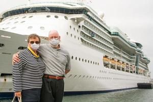 senior paar vervelend gezicht maskers staand in voorkant van passagier reis schip foto