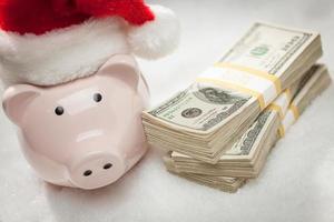 varkentje bank vervelend de kerstman hoed in de buurt stapels van honderd dollar rekeningen Aan sneeuwvlokken foto