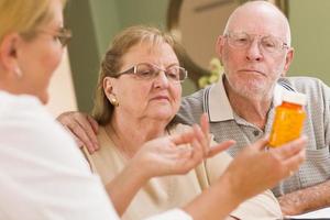 dokter of verpleegster uitleggen voorschrift geneeskunde naar senior paar foto