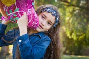 schattig jong gemengd ras meisje Holding mylar ballon buitenshuis foto