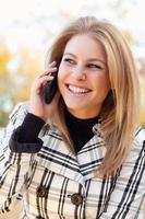 mooi jong blond vrouw Aan telefoon buiten foto