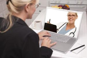 vrouw in keuken gebruik makend van laptop - online met verpleegster of dokter foto