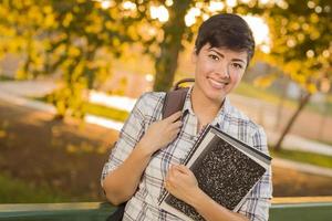 portret van een mooi gemengd ras vrouw leerling Holding boeken foto